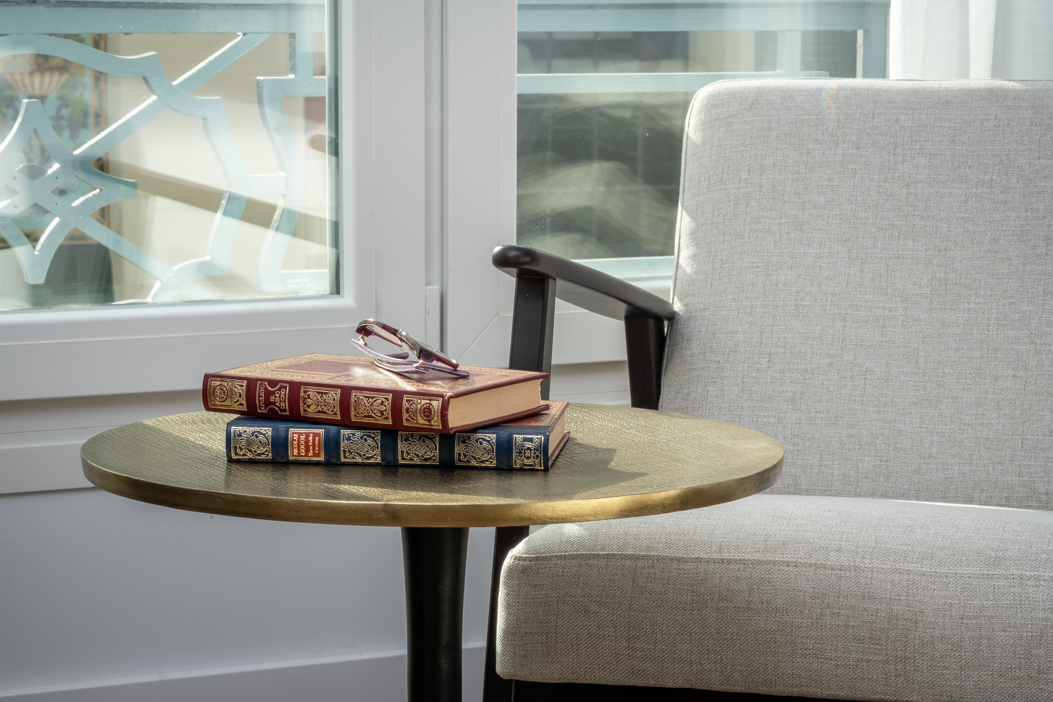 Rincón de lectura con libros y mesa de latón